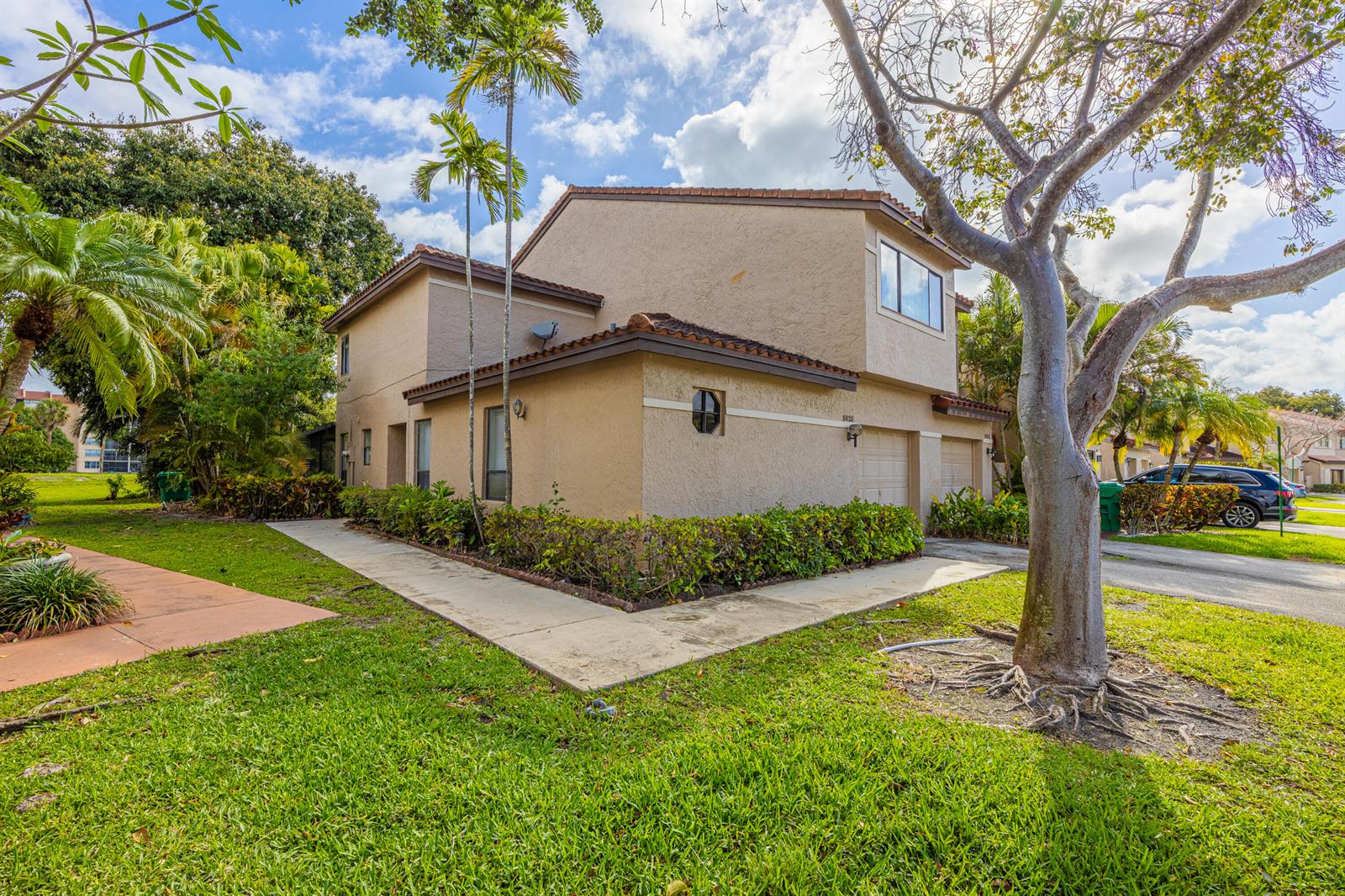 A two-story tan stucco townhouse with a garage and surrounding landscaping under a cloudy sky — 3625 Inverrary Boulevard W, Lauderhill FL 33319, LAUDERHILL, FL