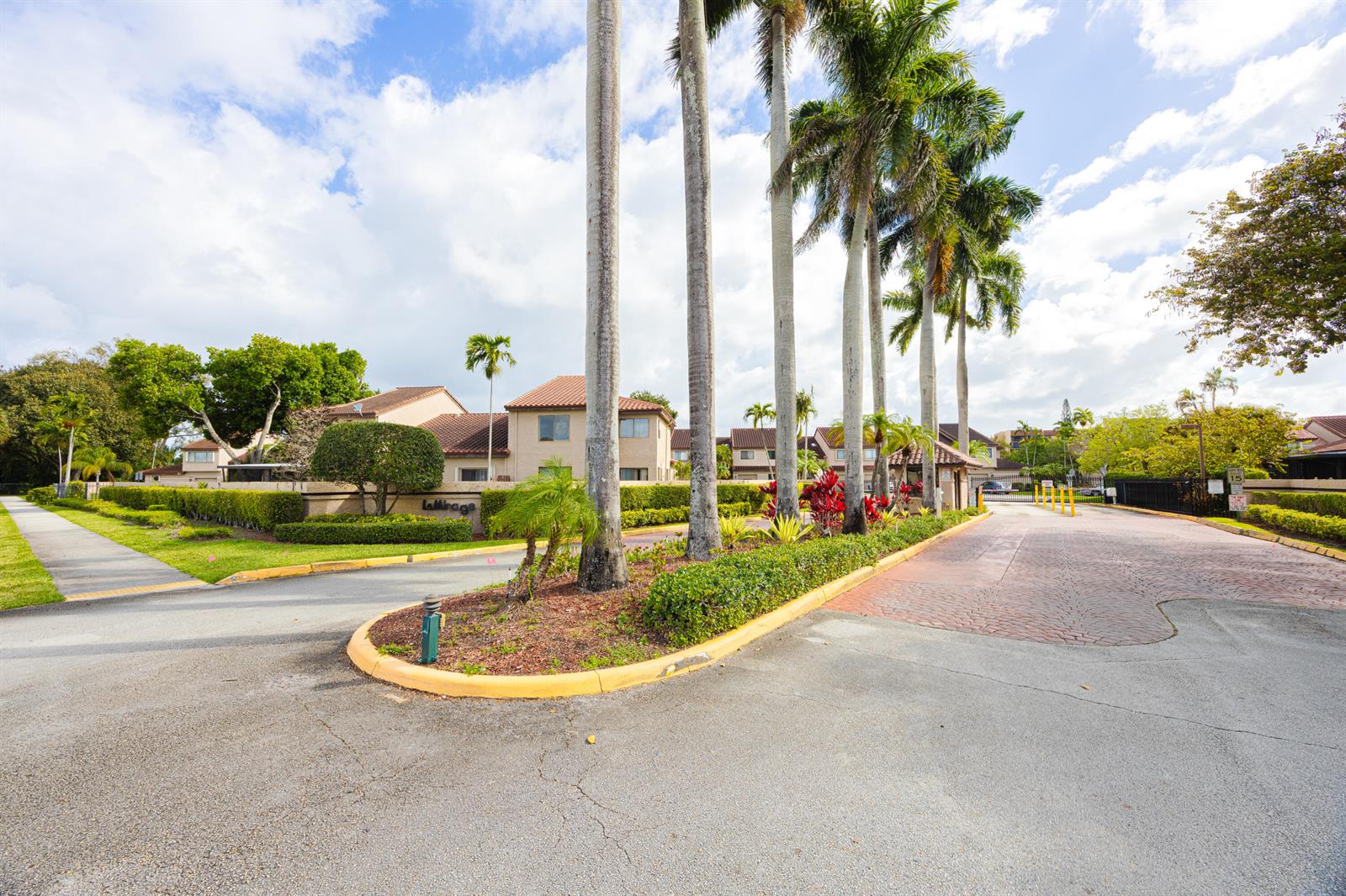A paved driveway leads to the entrance of a residential complex with tall palm trees — 3625 Inverrary Boulevard W, Lauderhill FL 33319, LAUDERHILL, FL