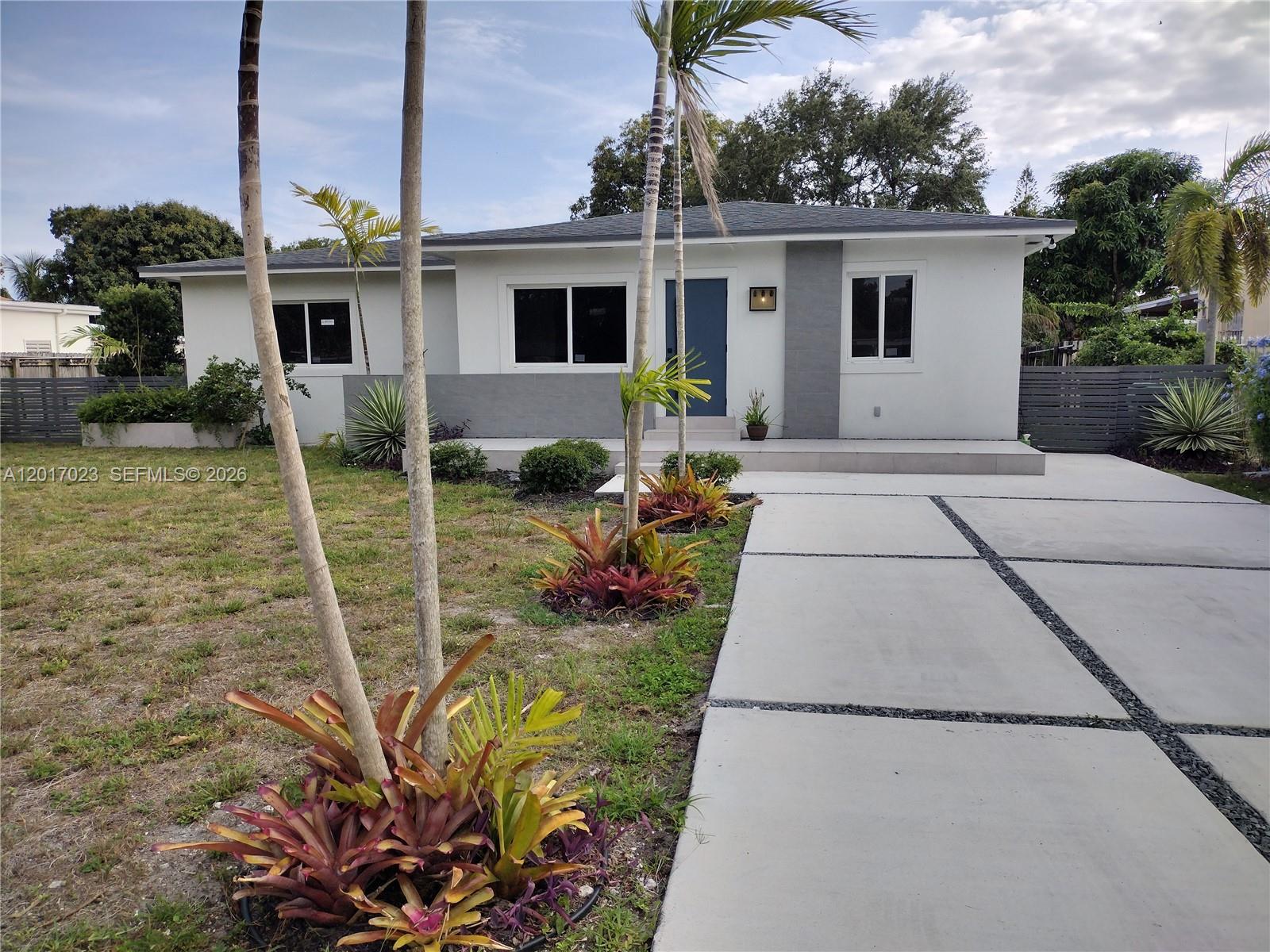 A single-story house with a white exterior, gray accents, a blue door, and palm trees — 300 S Biscayne River Dr, Miami FL 33169, MIAMI, FL