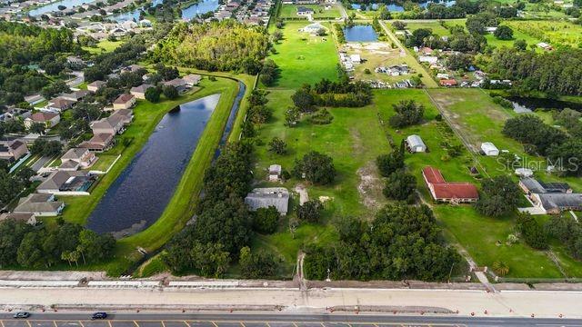 This aerial view shows a large, grassy plot of land adjacent to a residential neighborhood — 4121 BOGGY CREEK ROAD, KISSIMMEE, FL