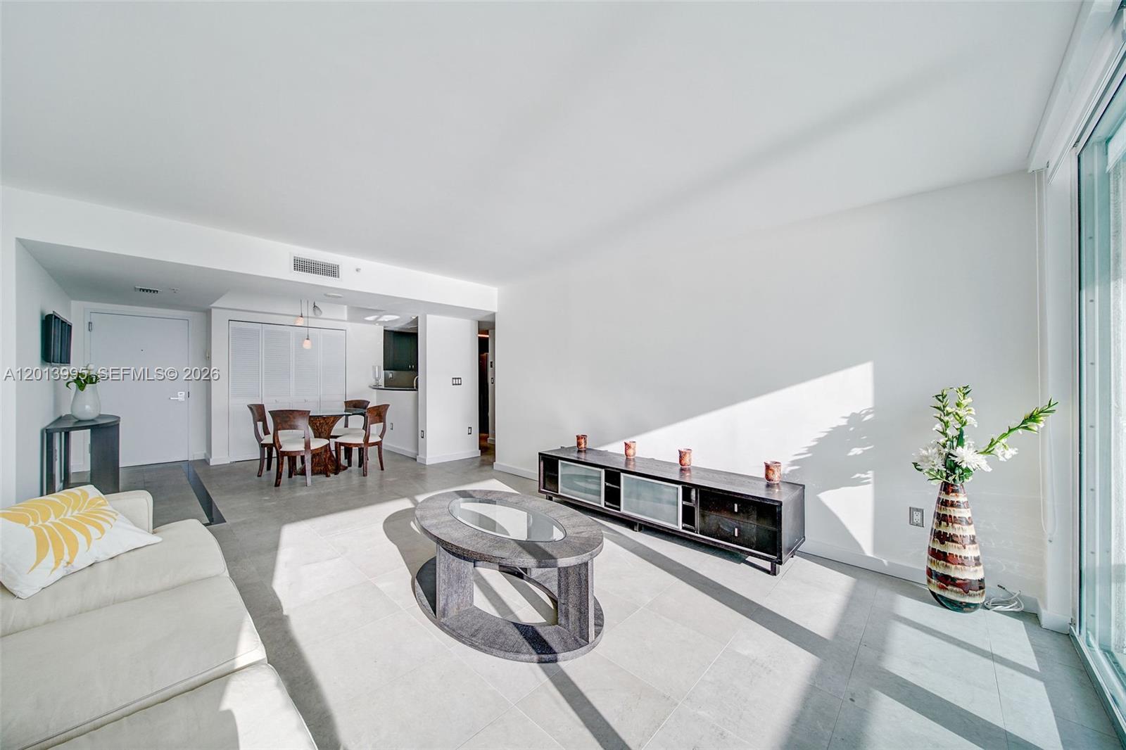 A bright living room features light tile floors, a white sofa, and a glass-topped coffee table — 650 West Ave # 805, Miami Beach FL 33139, MIAMI BEACH, FL