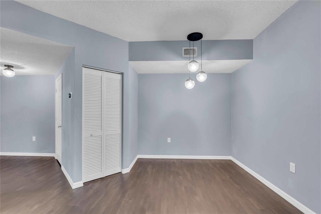 An empty dining area features light blue walls, dark wood flooring, and a modern pendant light — 4763 TRAVINI CIRCLE UNIT 3-303, SARASOTA, FL
