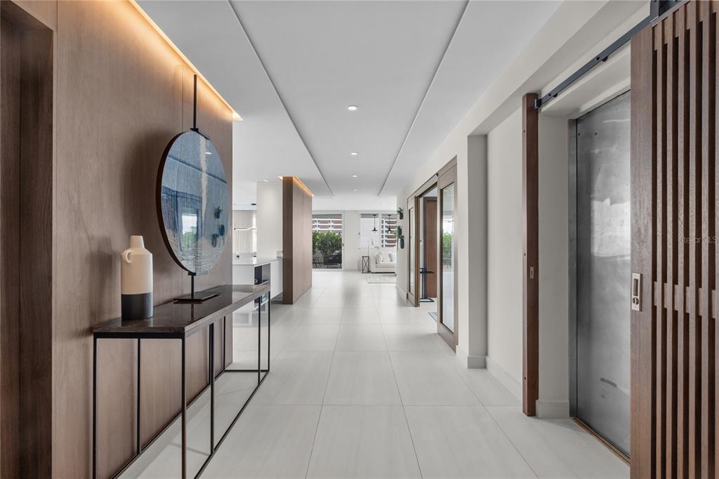 A modern hallway features light tile flooring, wood-paneled walls, and a decorative circular art piece — 1115 CALLE PICCIONI UNIT PH, SAN JUAN, PR