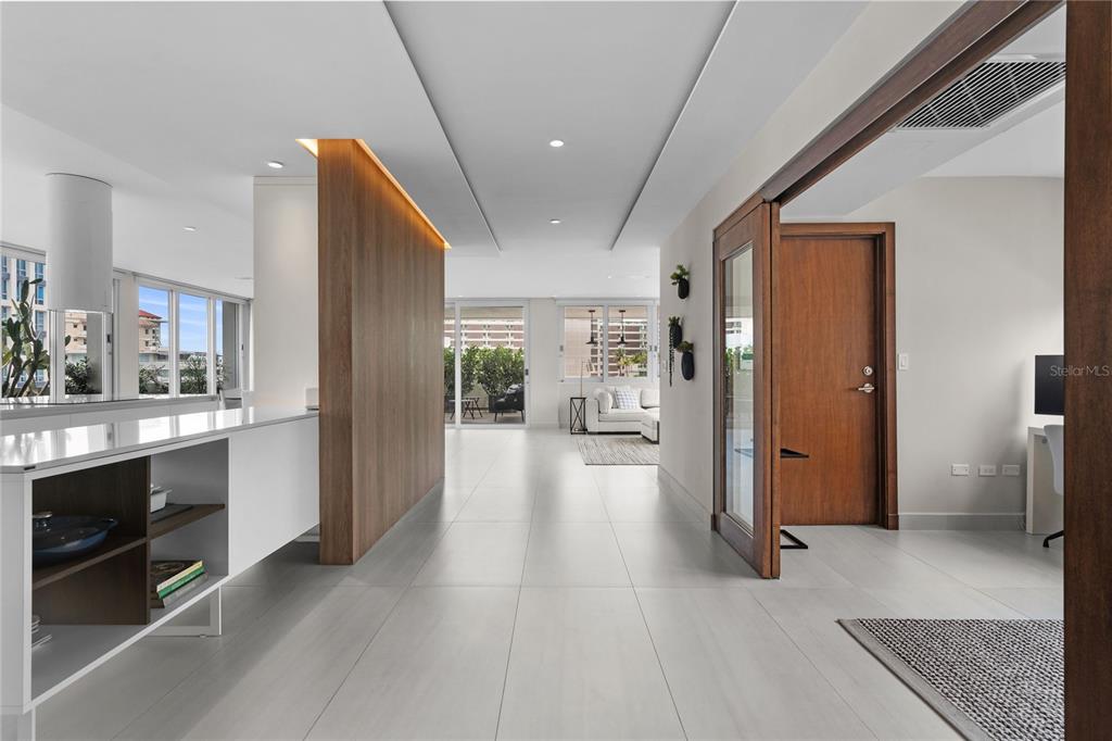 A modern interior features a white kitchen island, wood-paneled wall, and tiled flooring — 1115 CALLE PICCIONI UNIT PH, SAN JUAN, PR