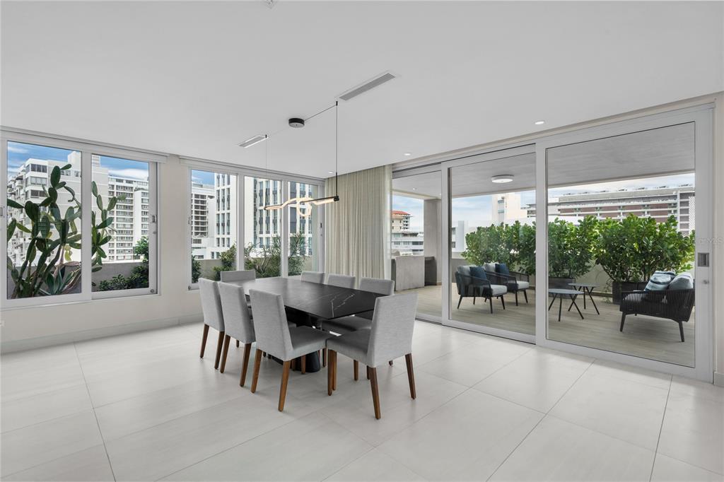 A modern dining room with a dark table, eight chairs, and large sliding glass doors — 1115 CALLE PICCIONI UNIT PH, SAN JUAN, PR