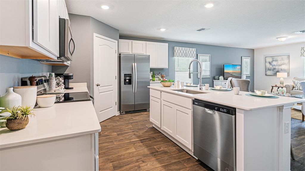 A modern kitchen features white cabinets, stainless steel appliances, and a central island with seating — 25 RYAPPLE LANE, PALM COAST, FL