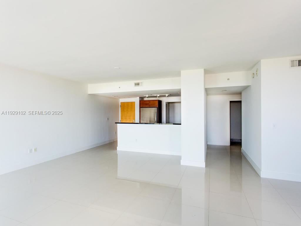 An open-concept living area features white walls, tile flooring, and a kitchen with dark cabinetry — 244 Biscayne Blvd # 2402, Miami FL 33132, MIAMI, FL