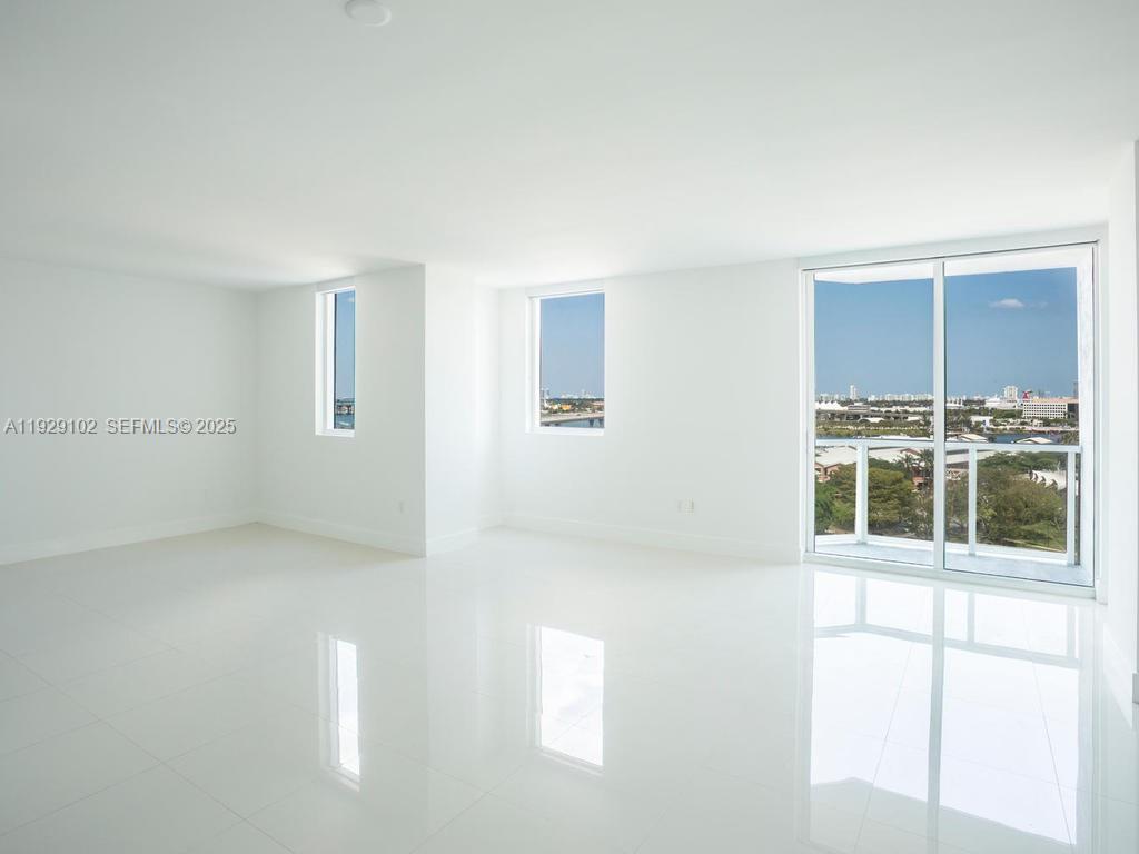 An empty room with white walls, glossy tile floors, and a balcony overlooking a city — 244 Biscayne Blvd # 2402, Miami FL 33132, MIAMI, FL