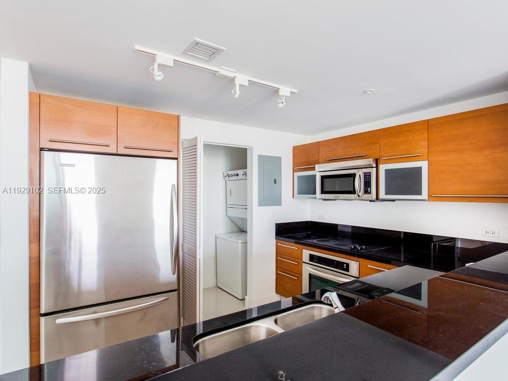 A kitchen features wood cabinets, stainless steel appliances, and black countertops — 244 Biscayne Blvd # 2402, Miami FL 33132, MIAMI, FL