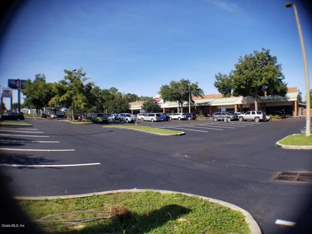 A parking lot in front of a commercial shopping center under a clear blue sky — 1927 SW COLLEGE ROAD UNIT B, OCALA, FL