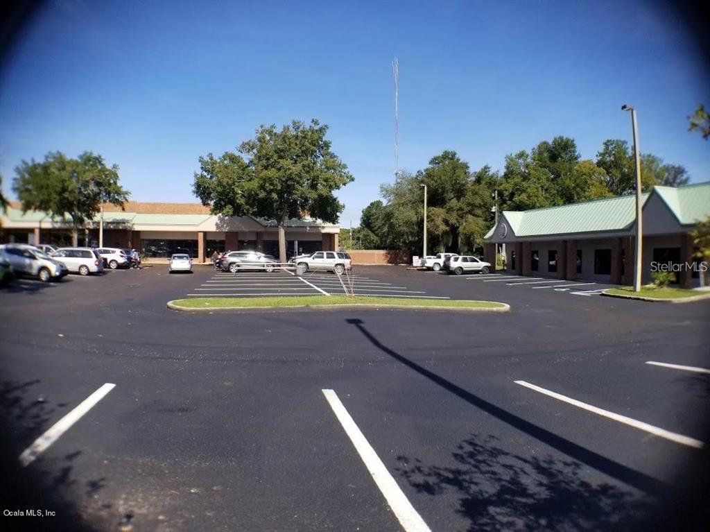 A paved parking lot sits in front of two single-story commercial buildings with green roofs — 1927 SW COLLEGE ROAD UNIT B, OCALA, FL