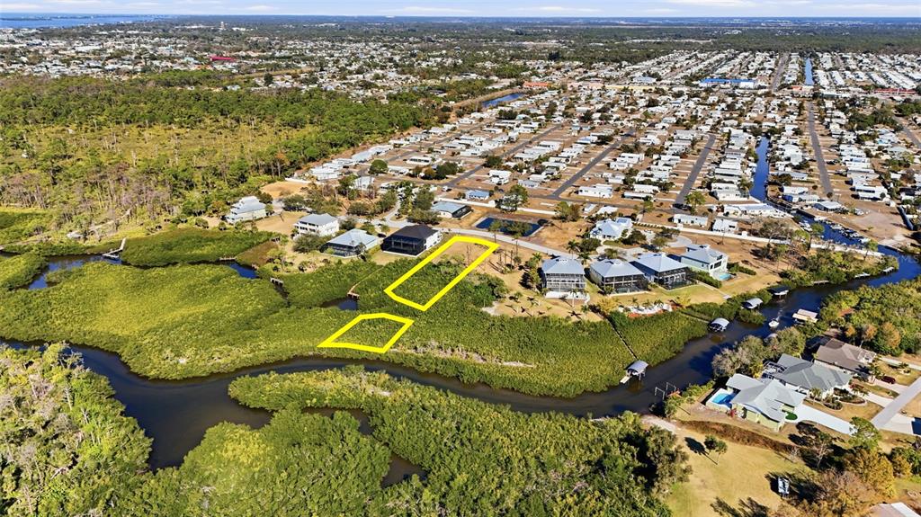 An aerial view shows a vacant lot outlined in yellow near a canal and mangroves — 8041 WEYERS COURT, ENGLEWOOD, FL