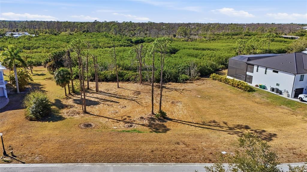 An elevated view of a vacant, grassy residential lot bordered by trees and a house — 8041 WEYERS COURT, ENGLEWOOD, FL