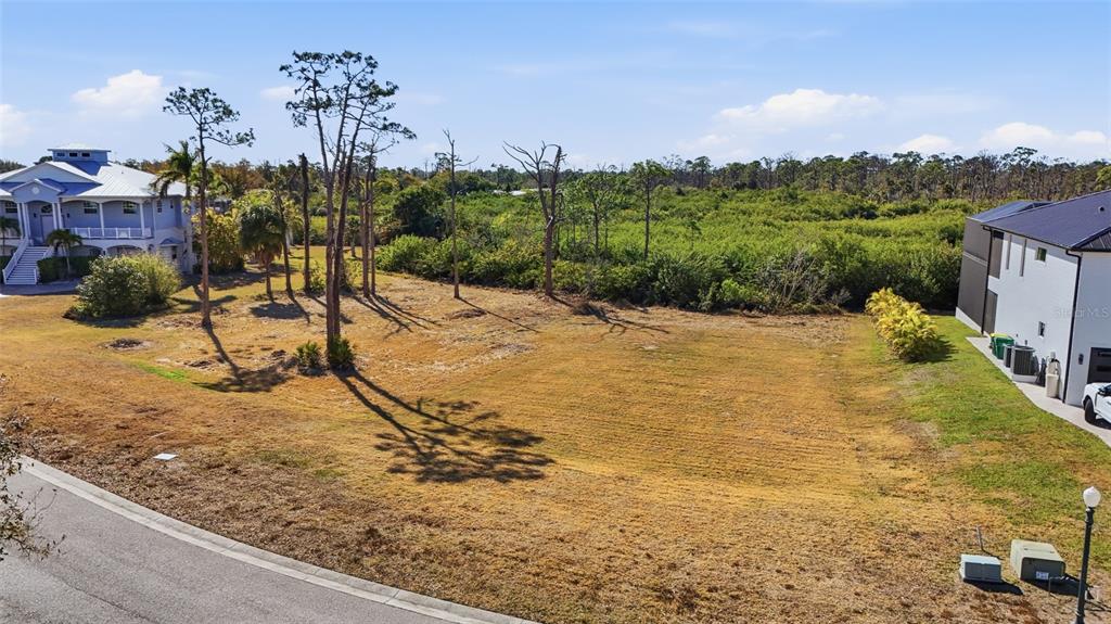 An elevated view of a vacant, grassy residential lot situated between two modern houses — 8041 WEYERS COURT, ENGLEWOOD, FL