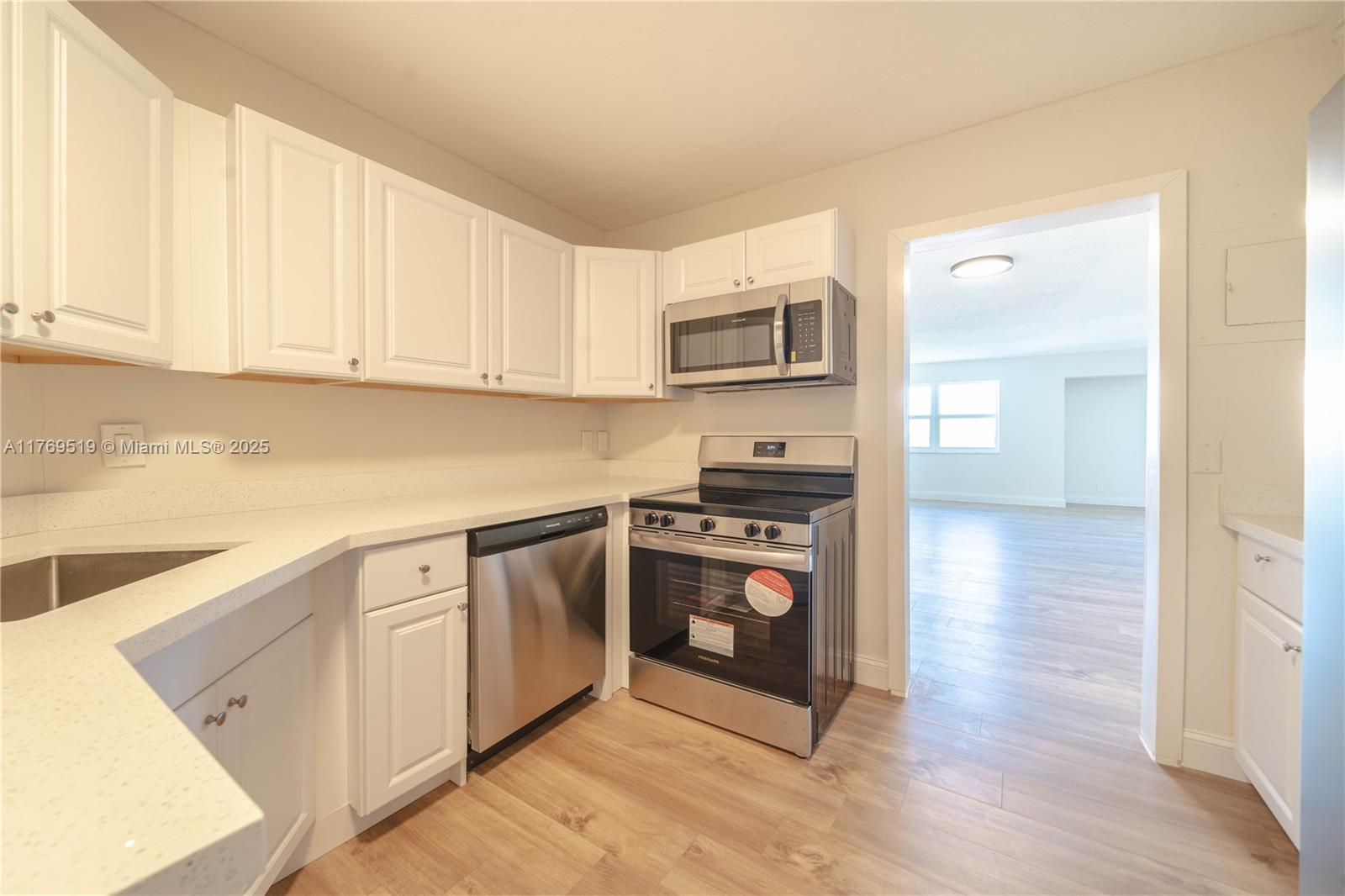 A kitchen features white cabinets, stainless steel appliances, and light wood-look flooring — 3301 Spanish Moss Ter # 802, Lauderhill FL 33319, LAUDERHILL, FL