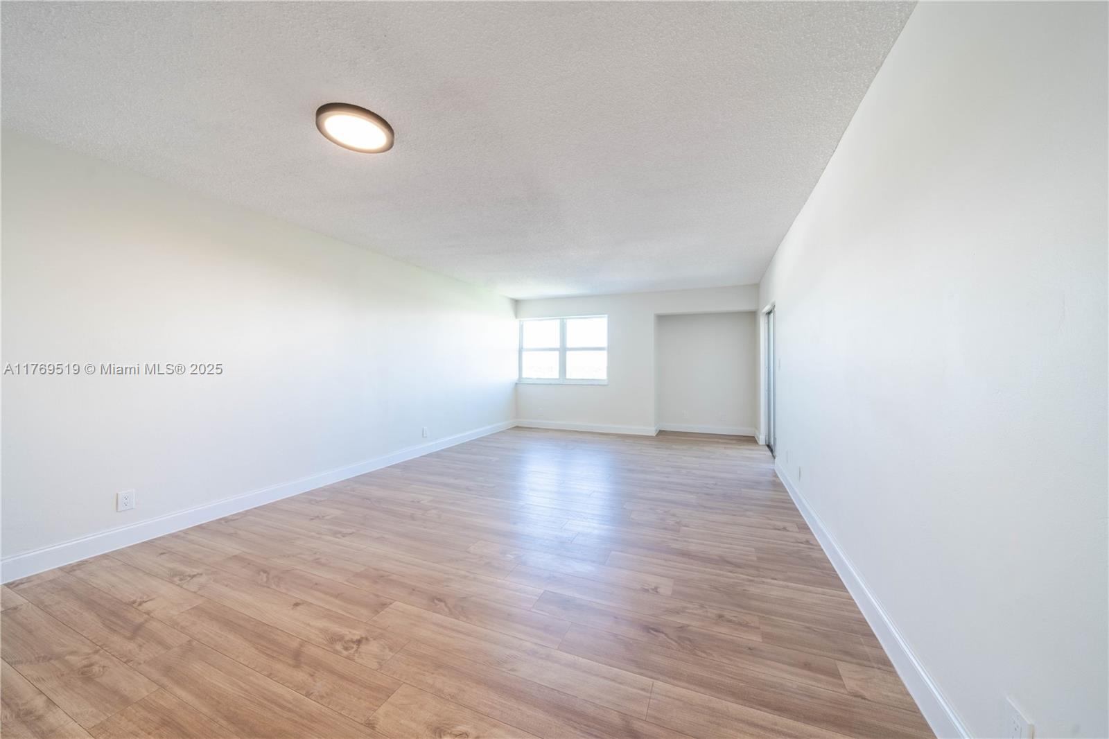 An empty room features white walls, light wood-look flooring, and a single ceiling light fixture — 3301 Spanish Moss Ter # 802, Lauderhill FL 33319, LAUDERHILL, FL