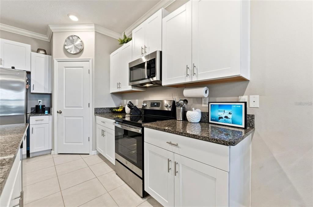 A kitchen features white cabinets, stainless steel appliances, and dark granite countertops — 31607 BLUE PASSING LOOP, WESLEY CHAPEL, FL