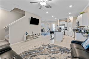 An open-concept living room and kitchen featuring white cabinetry, tile flooring, and a ceiling fan — 31607 BLUE PASSING LOOP, WESLEY CHAPEL, FL
