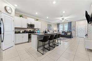 A kitchen with white cabinets and a center island opens into a living area — 31607 BLUE PASSING LOOP, WESLEY CHAPEL, FL
