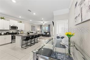 A modern kitchen with white cabinets, a large island, and an adjacent dining area — 31607 BLUE PASSING LOOP, WESLEY CHAPEL, FL