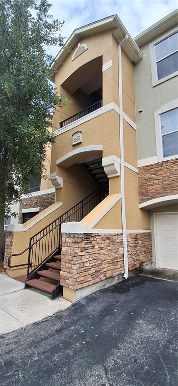 An exterior view of a multi-story apartment building featuring tan stucco and stone veneer siding — 8539 GATE PARKWAY W UNIT 1737, JACKSONVILLE, FL