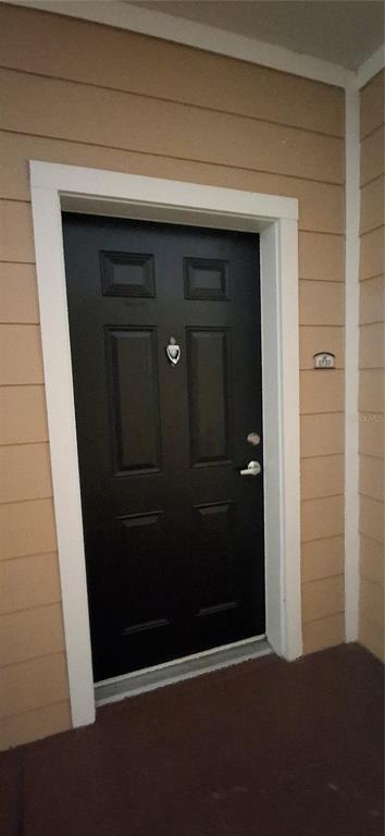 A black front door with a silver knocker and handle is set in a tan wall — 8539 GATE PARKWAY W UNIT 1737, JACKSONVILLE, FL