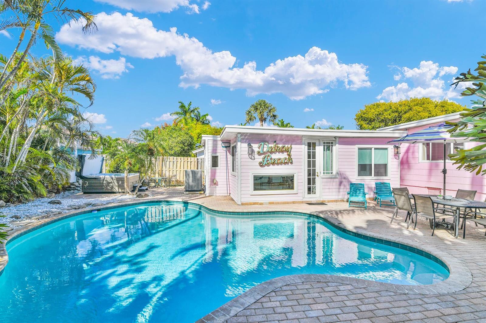 A pink house exterior features a swimming pool, patio furniture, and a hot tub — 3218 Palm Drive, Delray Beach FL 33483, DELRAY BEACH, FL