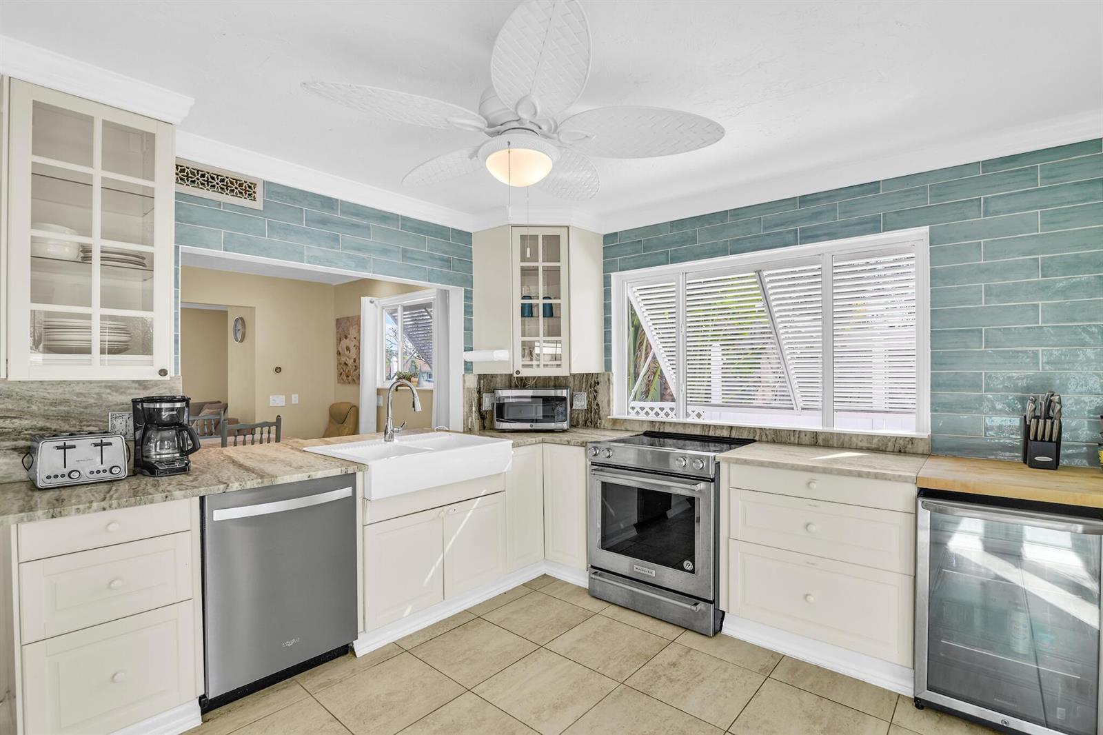 A kitchen features cream cabinets, blue subway tile backsplash, stainless steel appliances, and tile flooring — 3218 Palm Drive, Delray Beach FL 33483, DELRAY BEACH, FL
