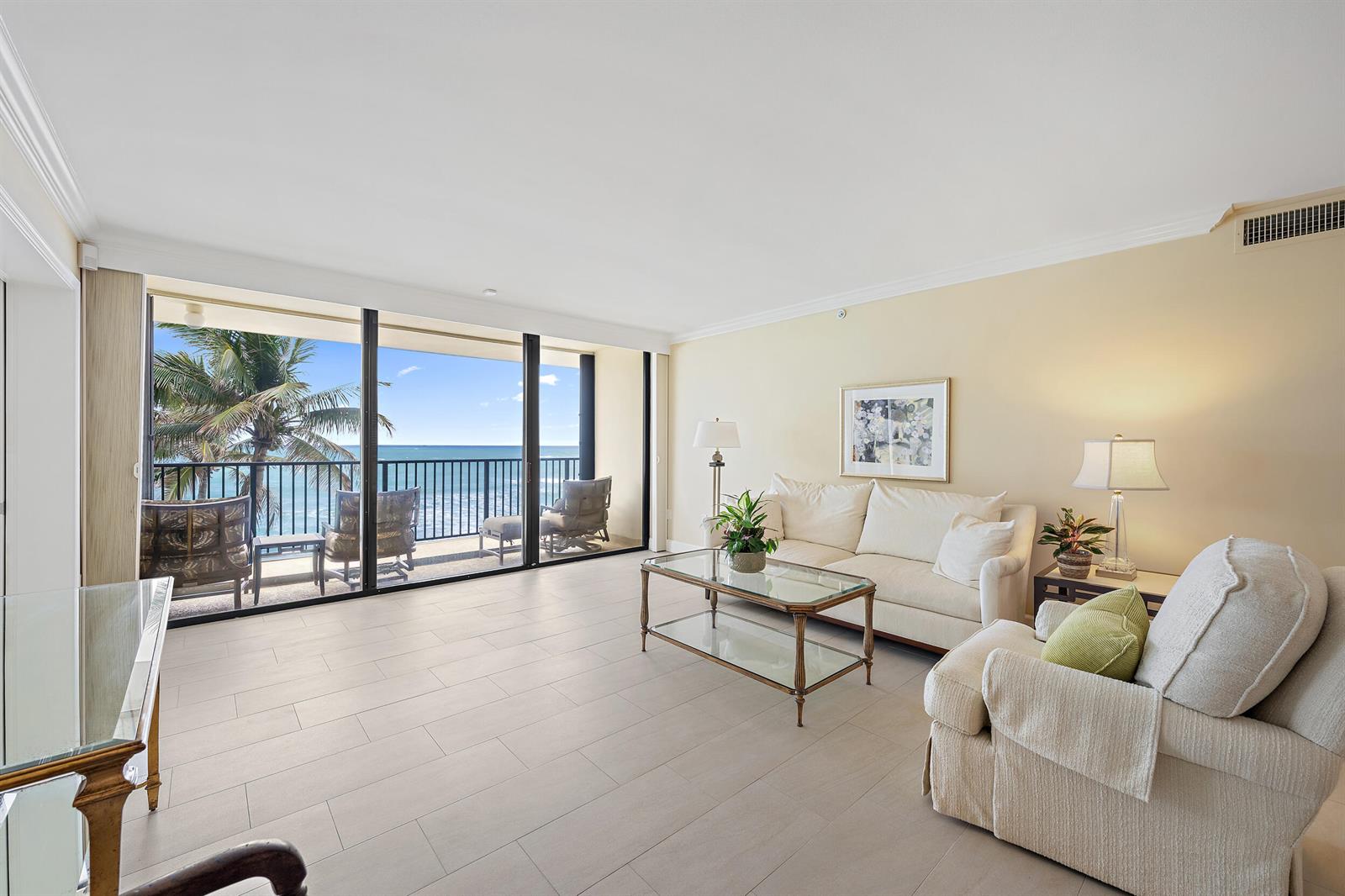 A living room with light tile floors features a sofa, armchair, and sliding glass balcony doors — 200 Beach Road # 202, Tequesta FL 33469, TEQUESTA, FL