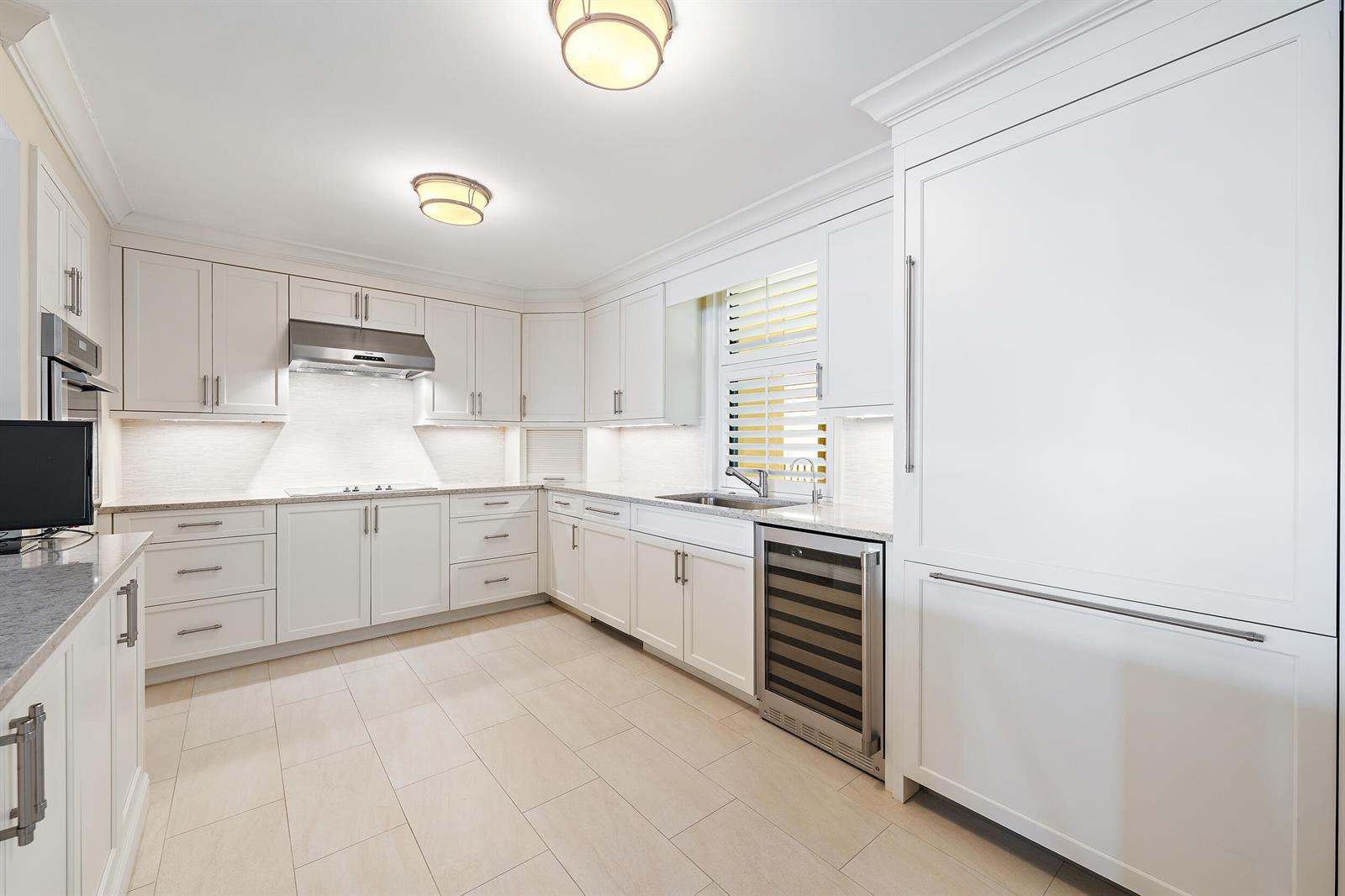 A bright kitchen features white cabinetry, stainless steel appliances, light countertops, and tile flooring — 200 Beach Road # 202, Tequesta FL 33469, TEQUESTA, FL