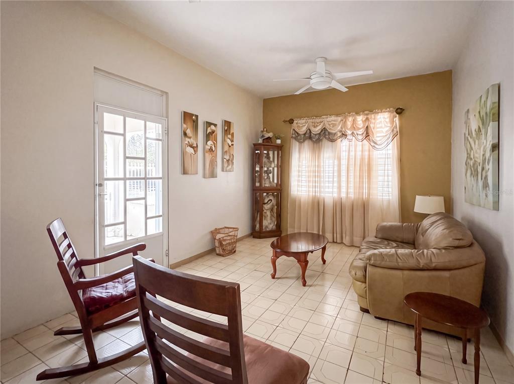 A living room features a tan sofa, a wooden rocking chair, and tiled flooring — 187 ROMAGUERA STREET, MAYAGUEZ, PR