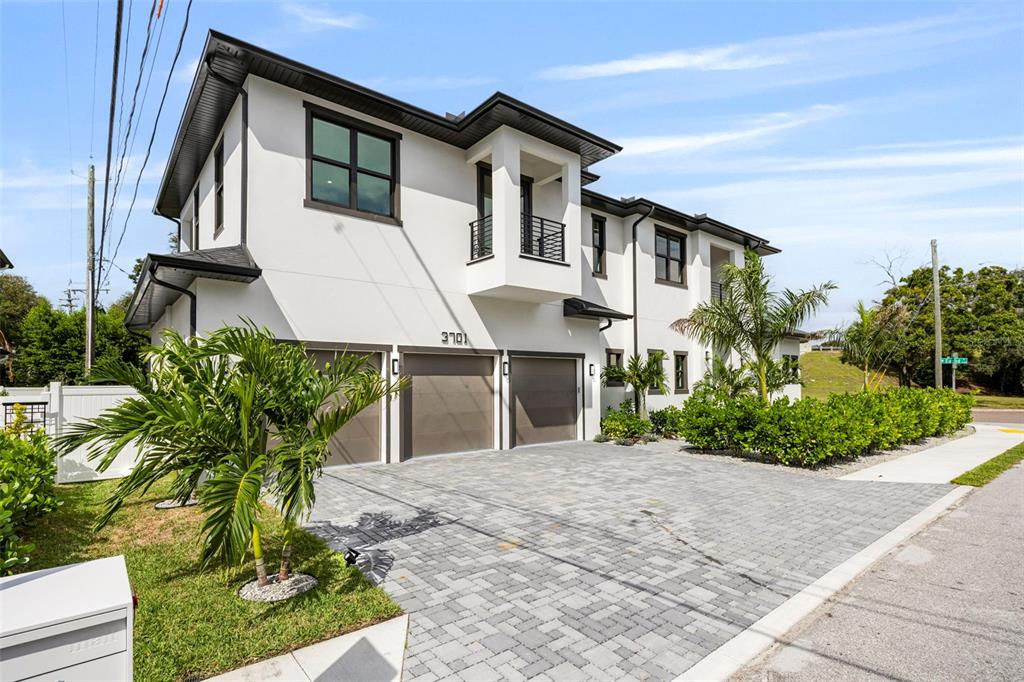 A two-story modern house with a paved driveway, three garage doors, and palm trees — 3701 S LYNWOOD AVENUE, TAMPA, FL