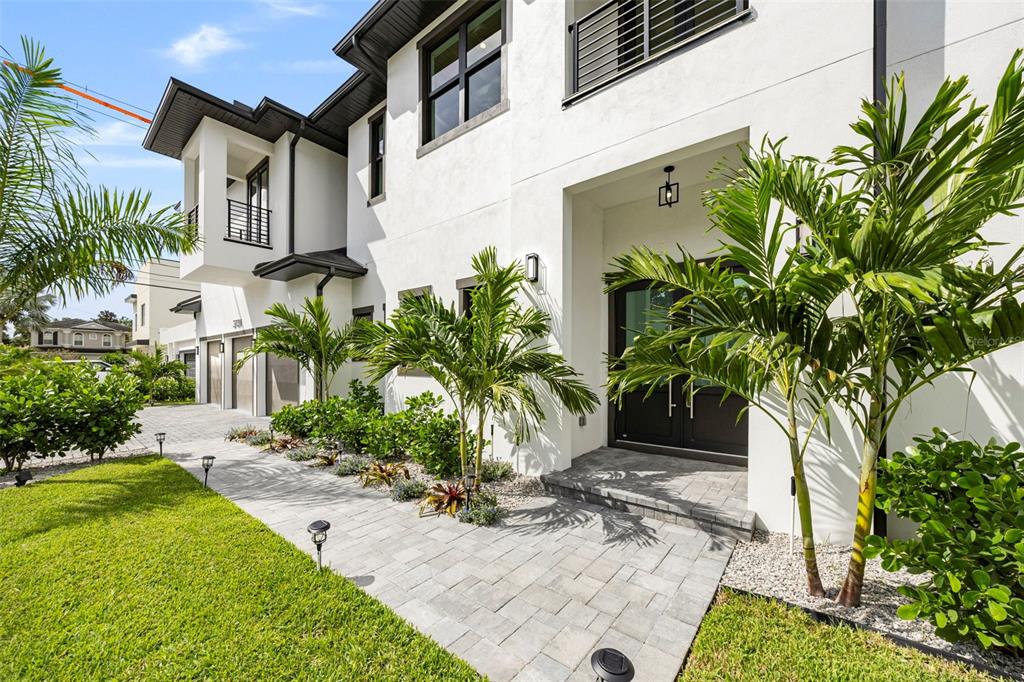 A modern white two-story house features a stone walkway, palm trees, and a dark entryway — 3701 S LYNWOOD AVENUE, TAMPA, FL