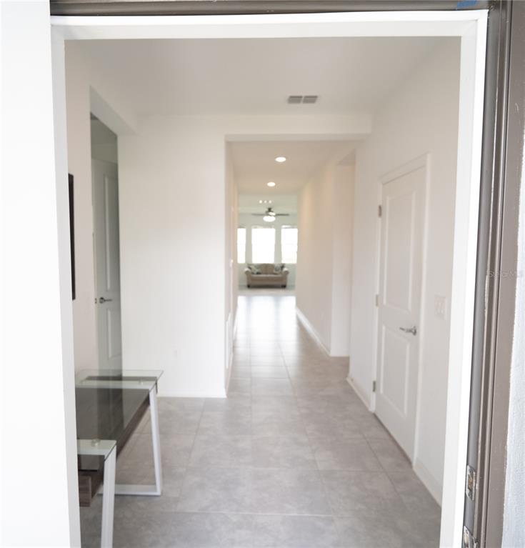 A view from a doorway looking down a tiled hallway toward a living area — 4211 LITTLE OWL LANE, KISSIMMEE, FL