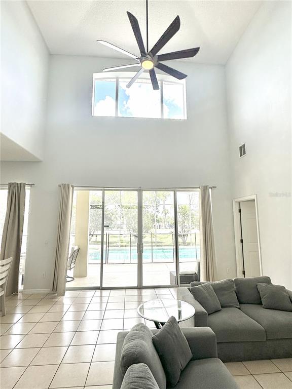 A living room with high ceilings, a large ceiling fan, and sliding glass doors — 1943 MORNING STAR DRIVE, CLERMONT, FL