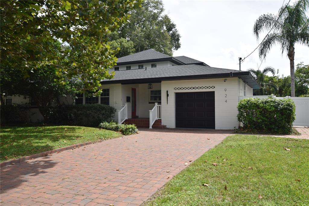A white single-story house with a black garage door and a brick driveway — 924 BOARDMAN STREET, ORLANDO, FL