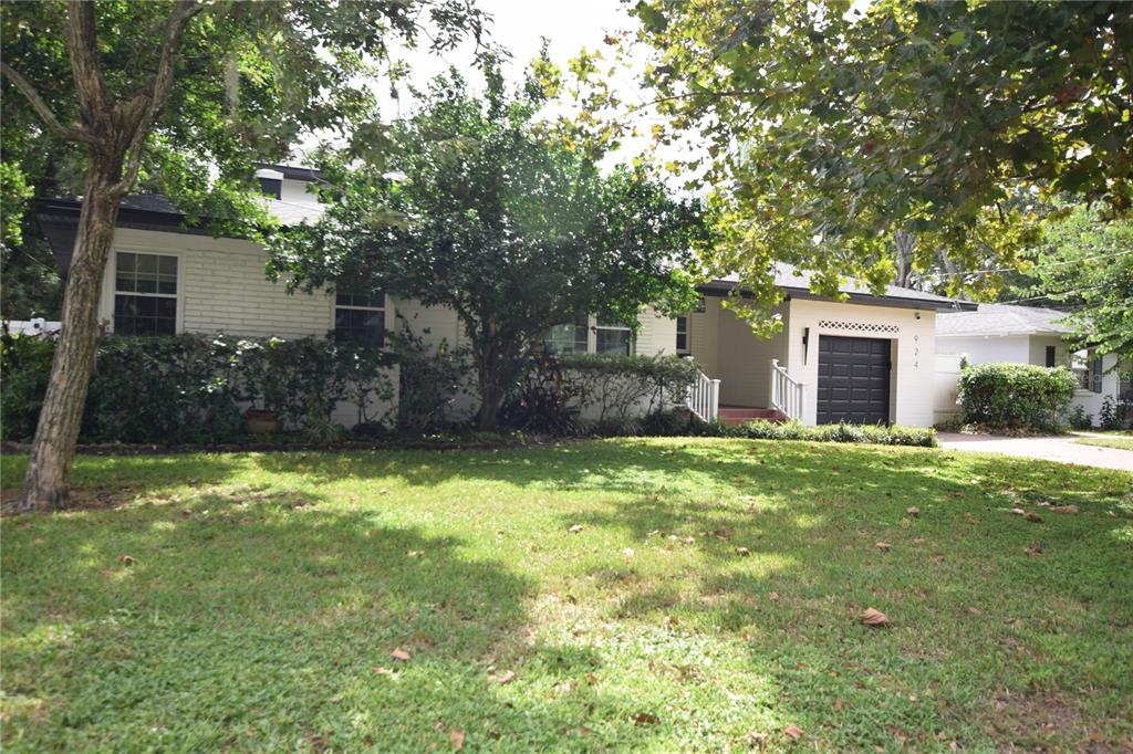 A single-story white brick house features a black garage door and a grassy front yard — 924 BOARDMAN STREET, ORLANDO, FL