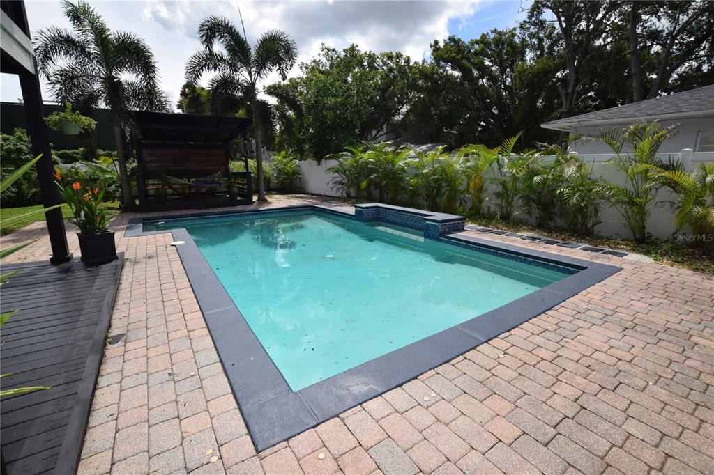 A rectangular swimming pool with a tiled border sits on a brick patio outdoors — 924 BOARDMAN STREET, ORLANDO, FL