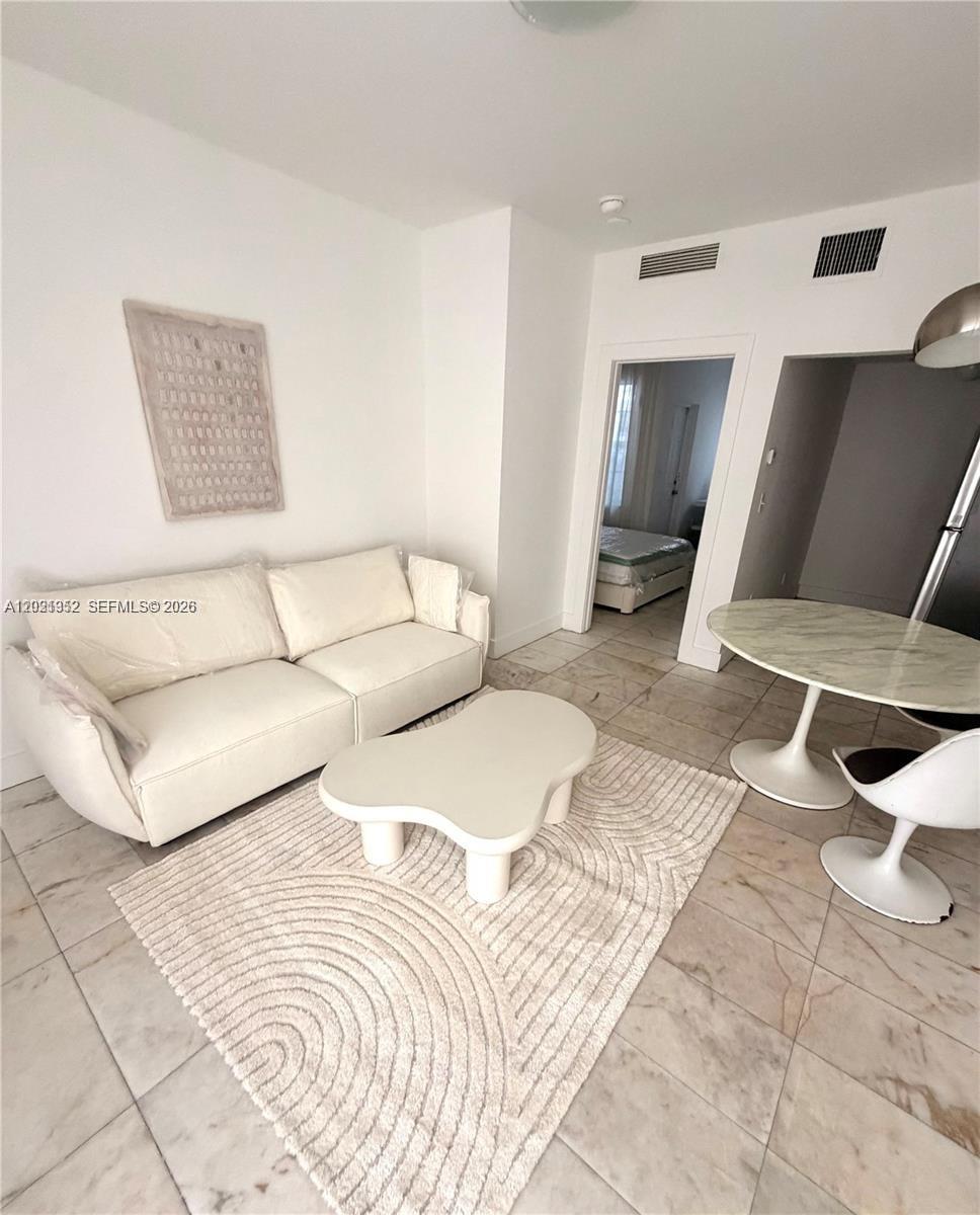 A living room features a white sofa, a modern coffee table, and a dining set — 801 8th St # 104, Miami Beach FL 33139, MIAMI BEACH, FL