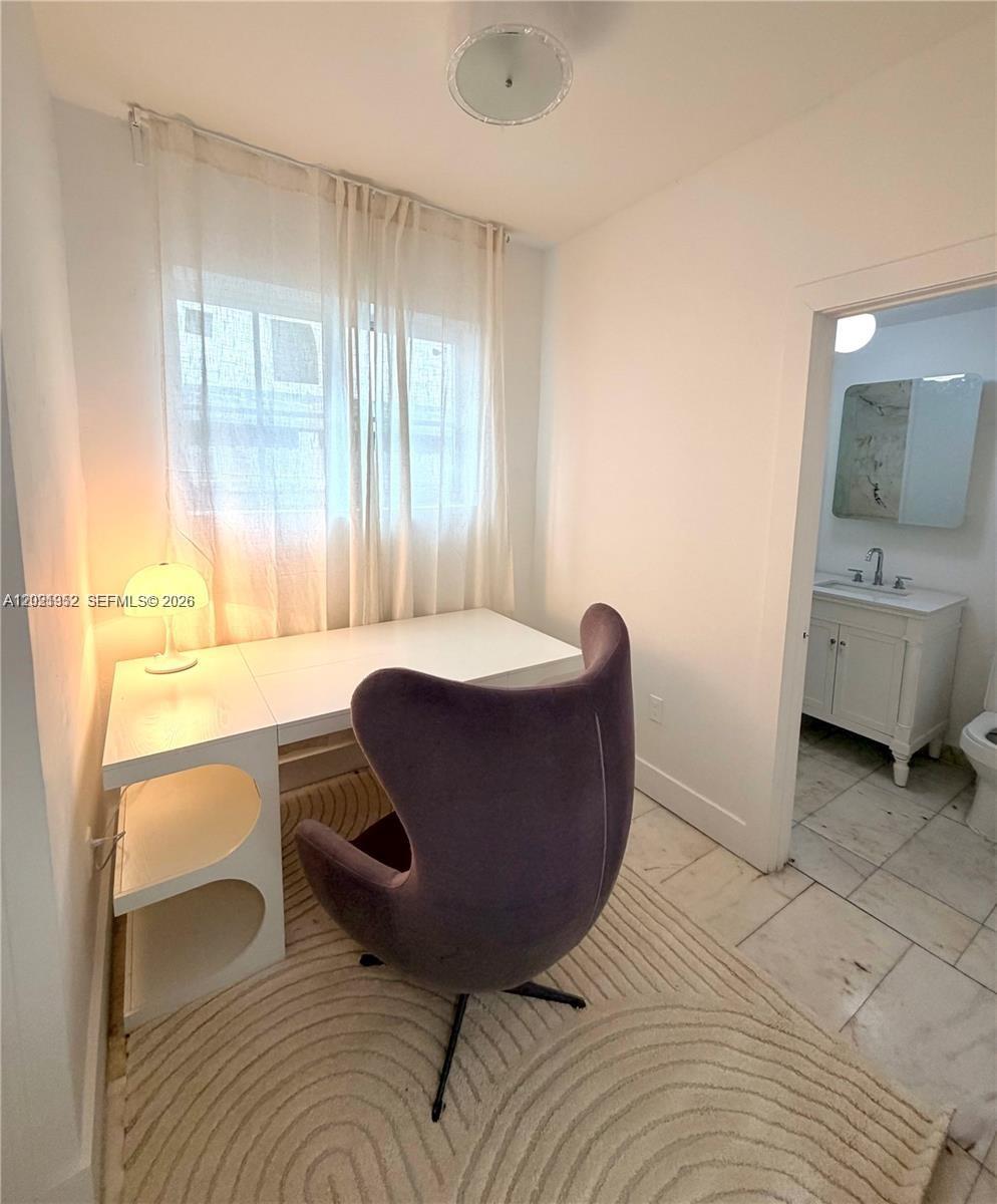 A small room features a white desk, a purple chair, and an adjacent bathroom — 801 8th St # 104, Miami Beach FL 33139, MIAMI BEACH, FL