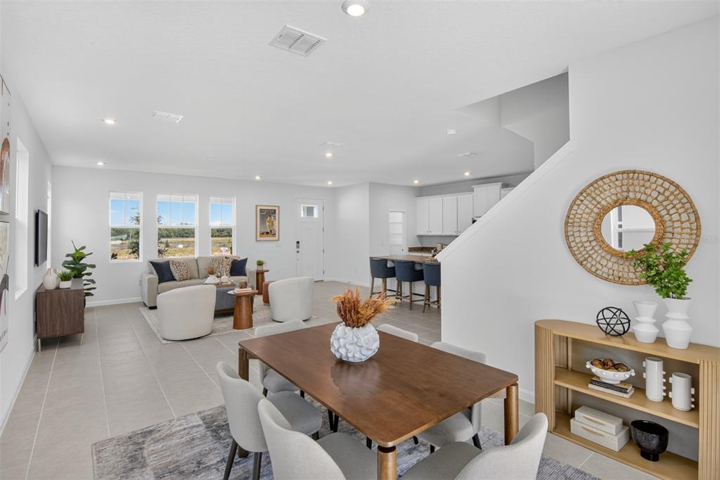 An open-concept living and dining area features tile flooring, a kitchen island, and neutral decor — 13439 GOOD VIBES AVENUE, ORLANDO, FL