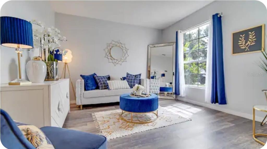 A living room features a white sofa, blue velvet ottoman, and blue curtains — 238 SUNSET VIEW DRIVE, DAVENPORT, FL