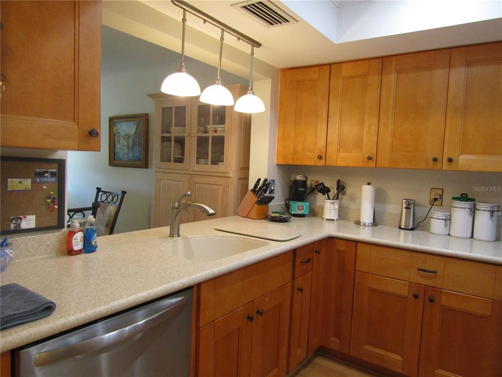 A kitchen features light wood cabinets, a white sink, and a three-light pendant fixture — 2961 TAYWOOD MEADOWS UNIT 26, SARASOTA, FL