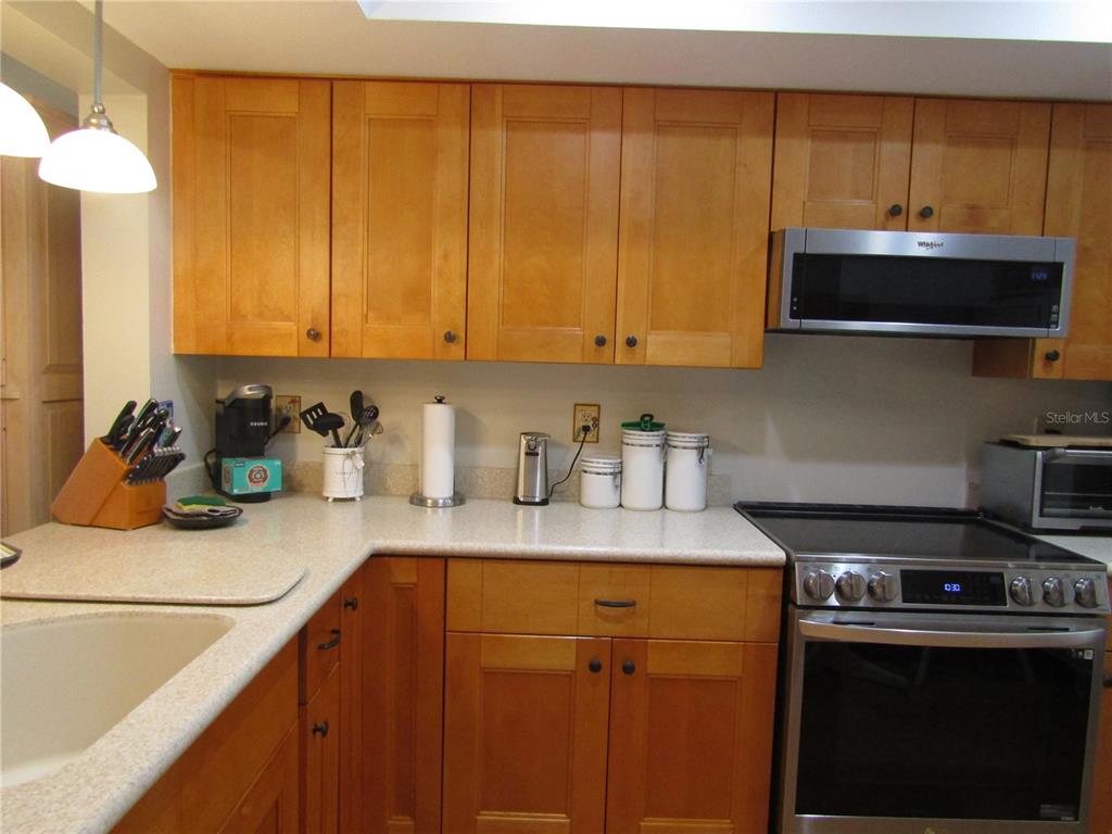 A kitchen features light wood cabinets, a stainless steel oven, and a light-colored countertop — 2961 TAYWOOD MEADOWS UNIT 26, SARASOTA, FL
