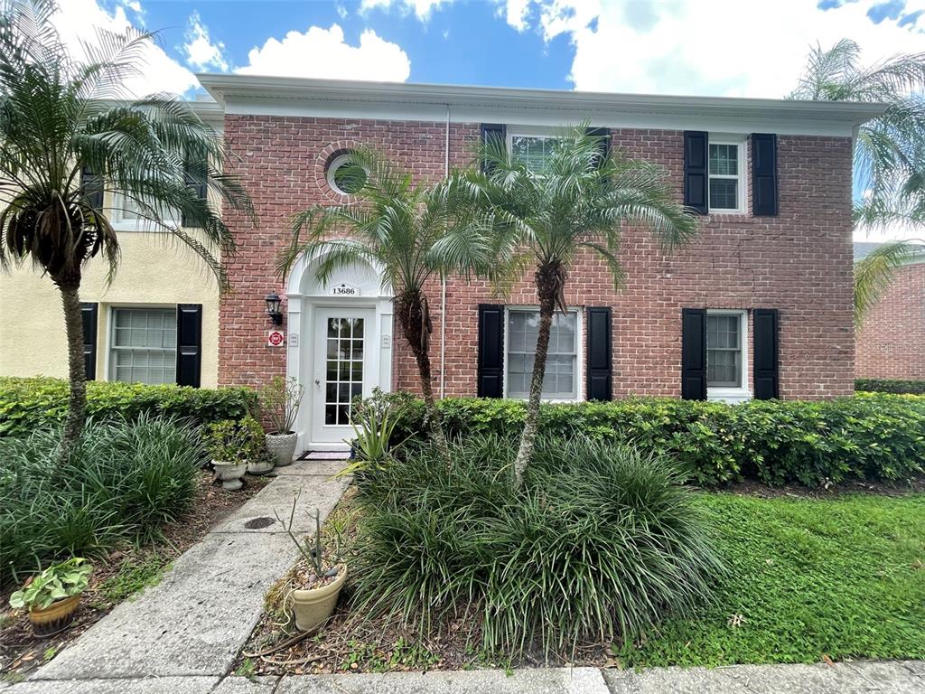 A two-story brick townhouse features a white arched front door and several palm trees — 13686 ORANGE SUNSET DR UNIT 201, TAMPA, FL