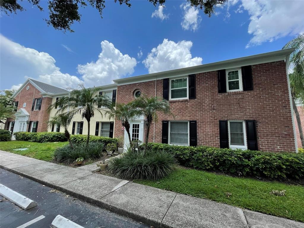 A two-story brick townhouse with black shutters, palm trees, and a sidewalk in front — 13686 ORANGE SUNSET DR UNIT 201, TAMPA, FL