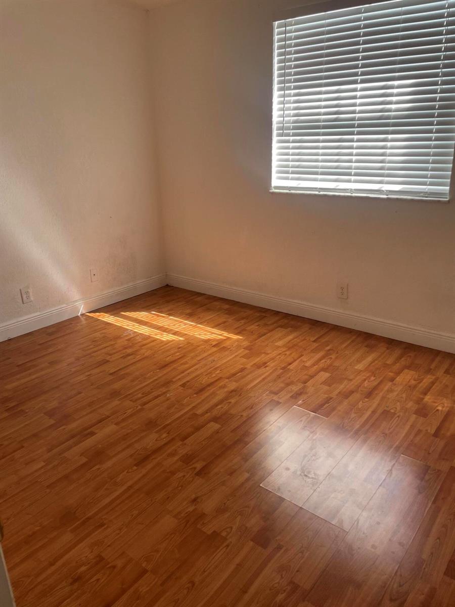 An empty room with light wood-look flooring, white walls, and a window with blinds — 8249 Fairway Road, Sunrise FL 33351, SUNRISE, FL