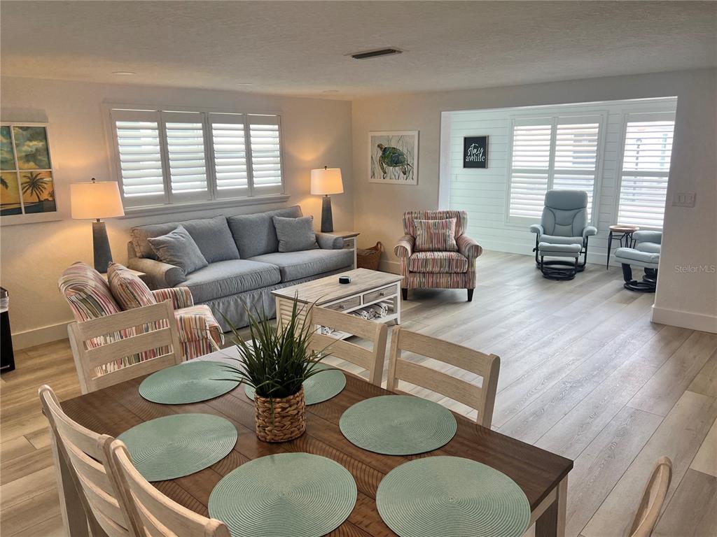 A dining area with a wooden table leads into a living room with gray furniture — 6154 MIDNIGHT PASS ROAD UNIT A15, SARASOTA, FL