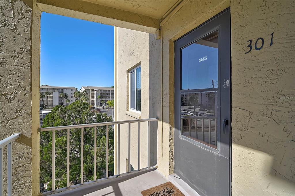 An outdoor balcony features a gray door labeled 301, a metal railing, and a doormat — 3585 LAKE BAYSHORE DRIVE UNIT J-301, BRADENTON, FL