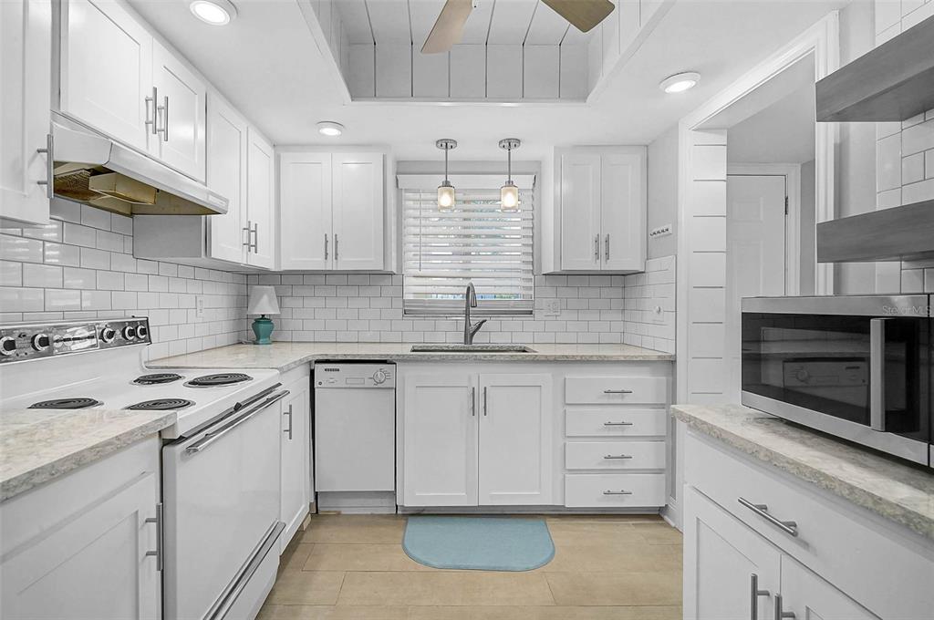 A white kitchen features subway tile backsplashes, light countertops, and stainless steel appliances — 3585 LAKE BAYSHORE DRIVE UNIT J-301, BRADENTON, FL